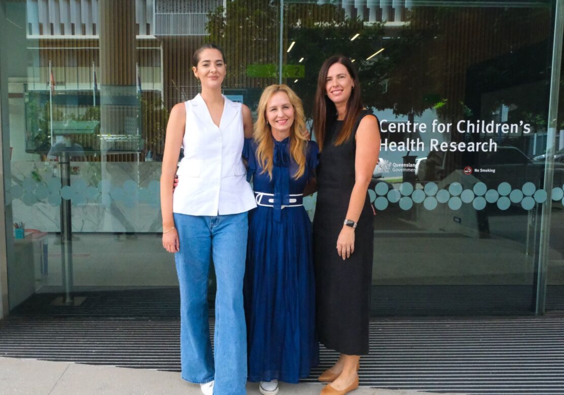 Three women stand in front of a research centre to announce a new grant program