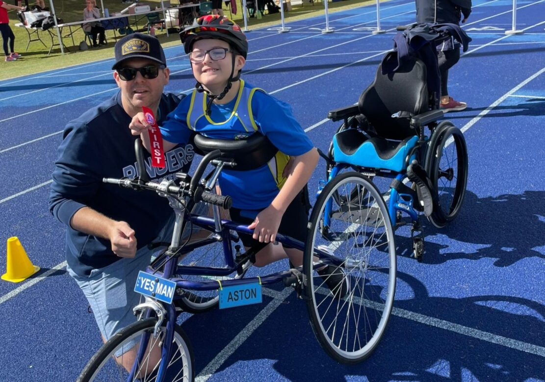 A boy with cerebral palsy holds a first ribbon for frame running