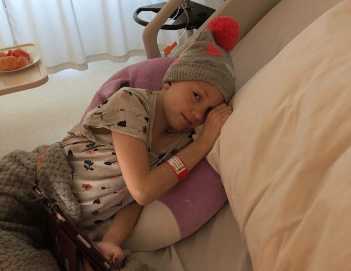 A young girl with cancer lies down in her bed