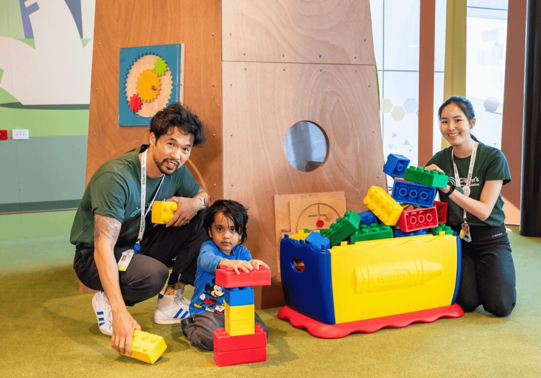 Two Children's Hospital Foundation volunteers play with a patient at Queensland Children's Hospital