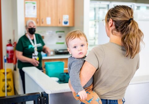Woman holds child while speaking to Children's hospital Foundation volunteer