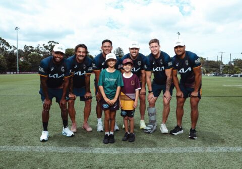 Brisbane Broncos players with children on the footy field