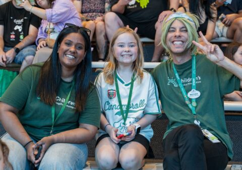 Two Children's Hospital Foundation employees smiling with young patient
