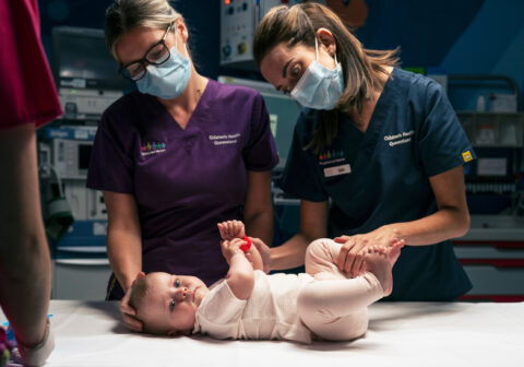 Three QCH nurses look after sick baby in hospital treatment room