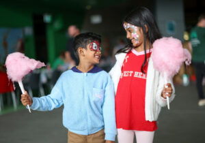 Two children smiling at each other eating fairy floss