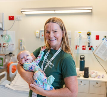 Cuddle Care volunteer cuddles smiling newborn